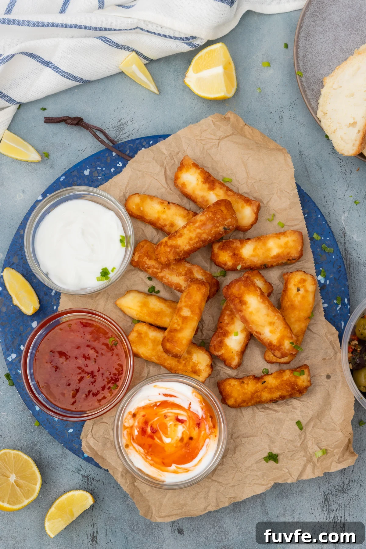 Crispy Halloumi Fries Recipe: Golden, Crunchy Cheese Fries 6 A blue marble platter of halloumi fries with 3 small bowls of dips from above on a blue background