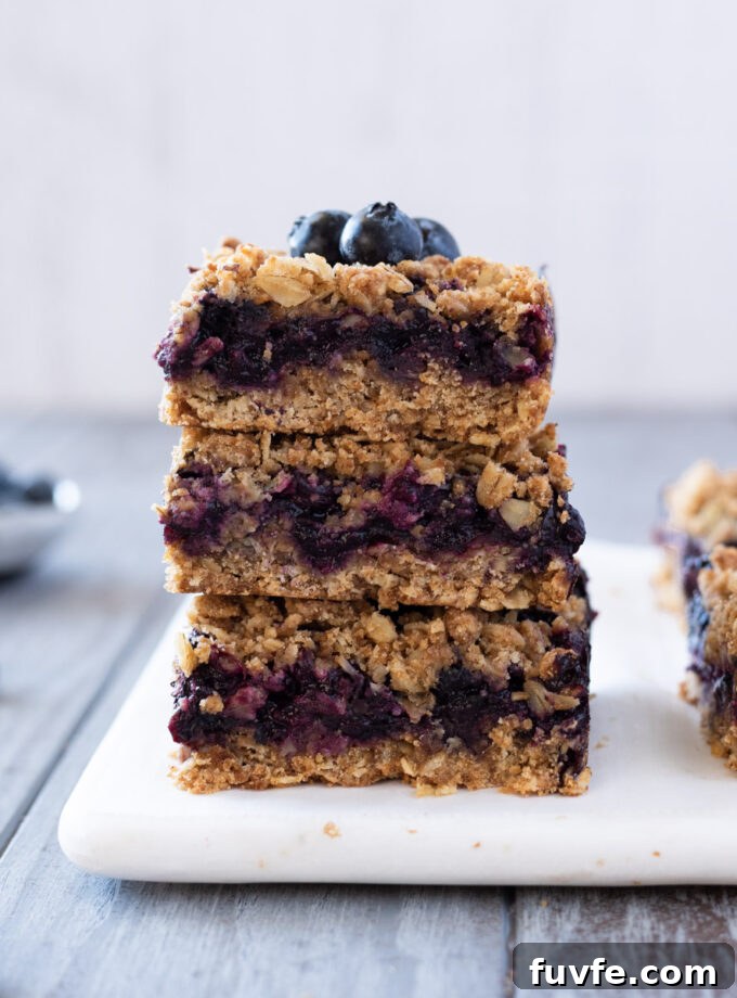 Blueberry Crumble Bars Recipe with Oat Crust 2 Stack of blueberry crumble bars with blueberries on top.