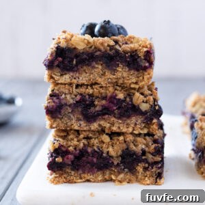Blueberry Crumble Bars Recipe with Oat Crust 12 Stack of blueberry crumble bars with blueberries on top.