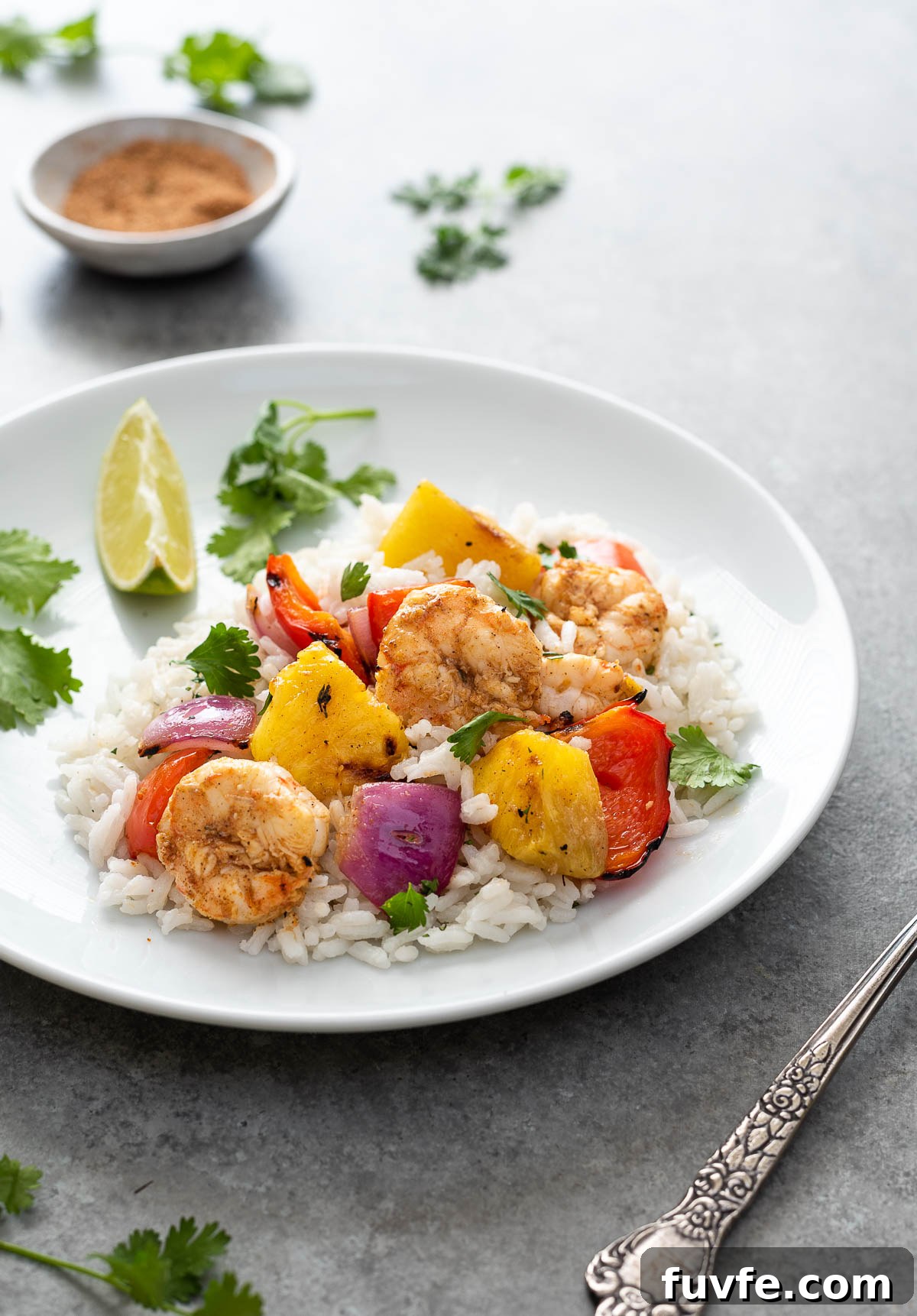 serving of pineapple shrimp skewers over rice on a white plate