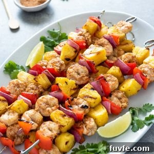 Grilled Jerk Shrimp and Pineapple Skewers 8 pineapple shrimp skewers on white serving platter with cilantro and lime