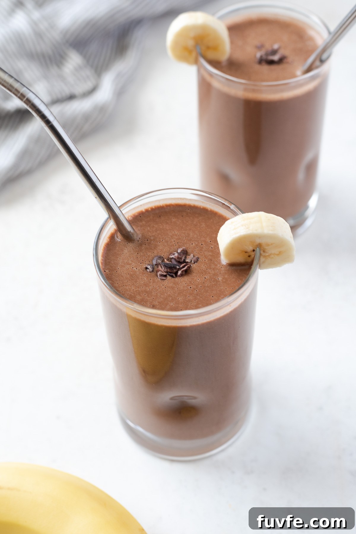 glass of chocolate banana protein smoothie with cacao nibs and banana on top