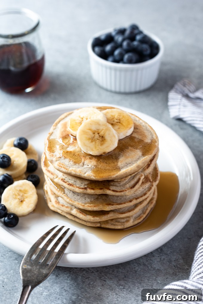 Gluten-Free Oat Flour Pancakes Recipe 3 Fluffy oat flour pancakes on a plate with bananas and blueberries