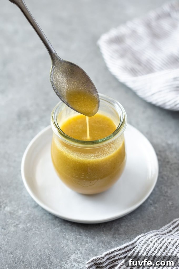 Apple cider dressing pouring from a spoon into a jar