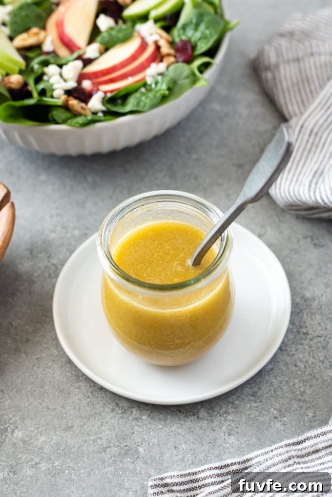Apple cider vinegar salad dressing in a jar with spoon and salad in background