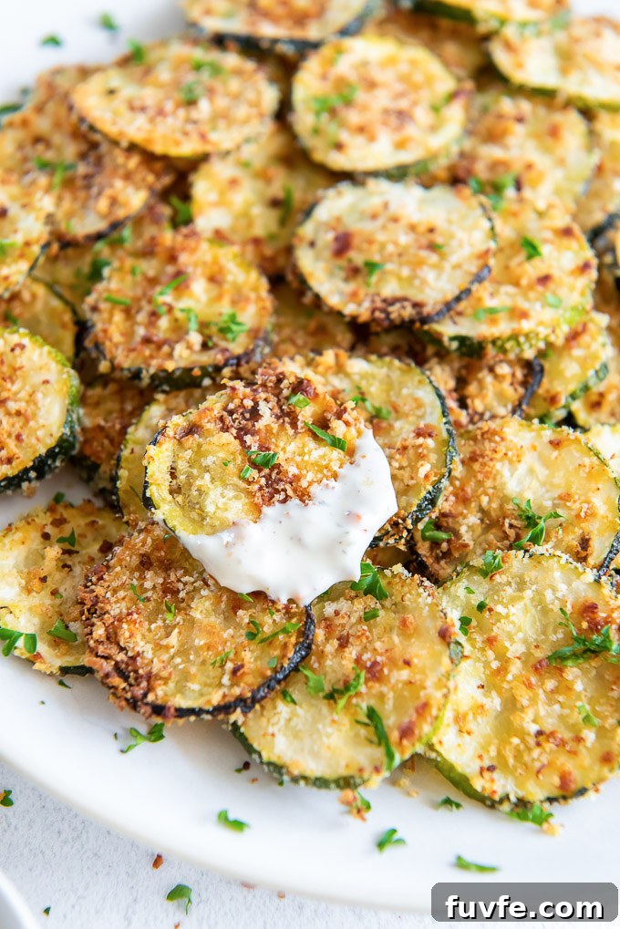 Crispy Oven-Baked Zucchini Chips Recipe 7 Plate of zucchini chips with one coated with ranch dressing