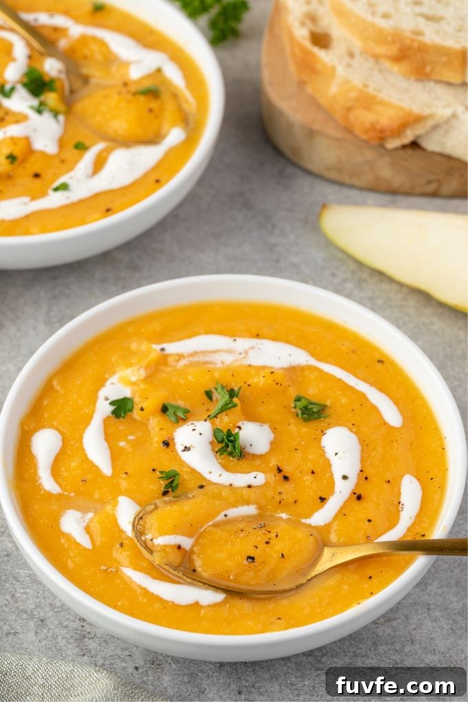 Spoon digging into bowl of roasted butternut squash soup with pears
