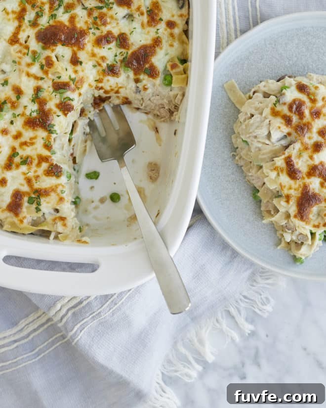 a serving of tuna noodle casserole on a plate next to a casserole dish of tuna noodle casserole