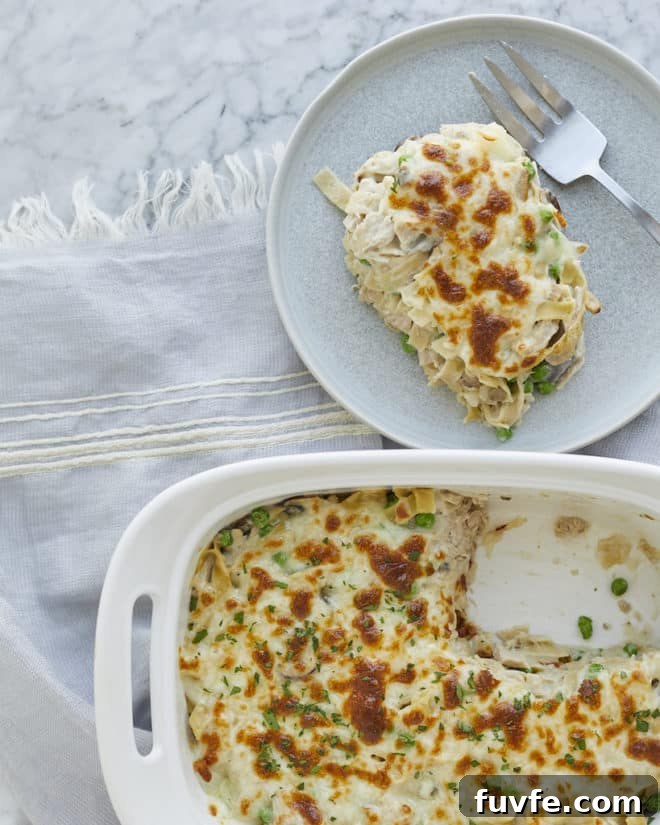 a serving of tuna noodle casserole on a plate next to a casserole dish of tuna noodle casserole