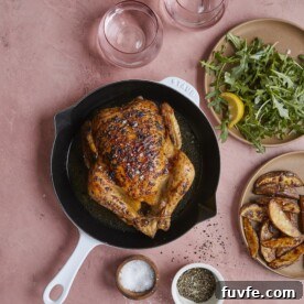 roasted chicken next to arugula salad and roasted potato wedges