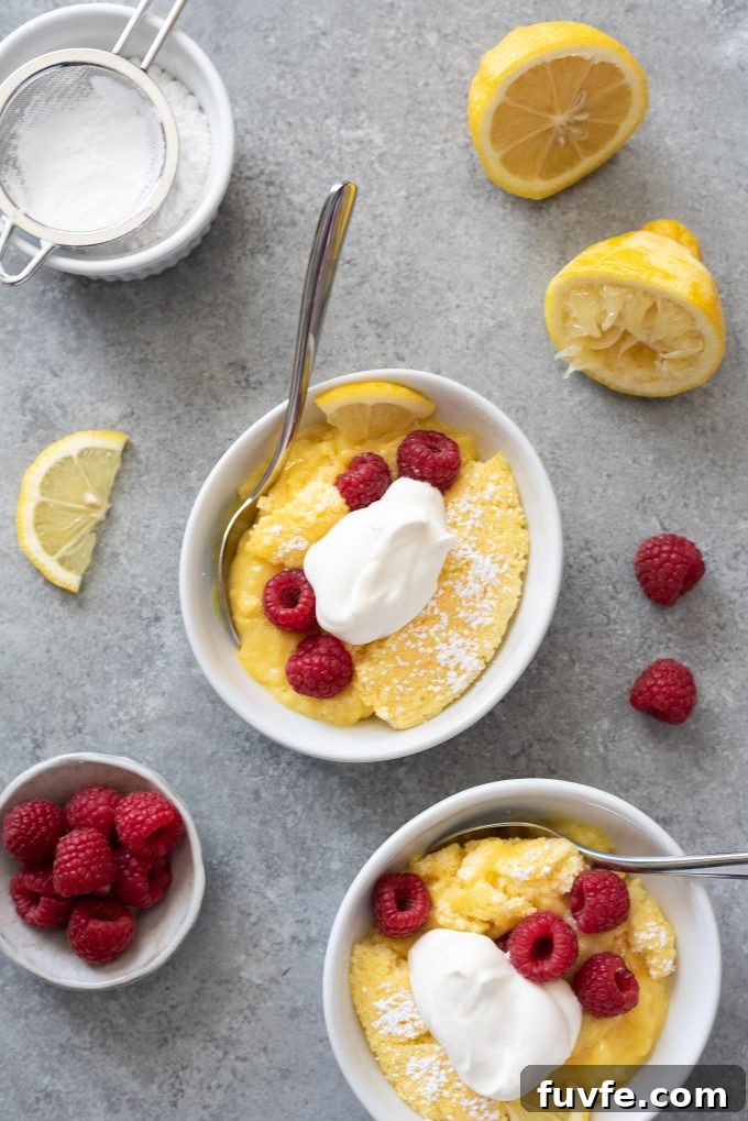 Lemon Pudding Cake Recipe with Silky Custard 2 Lemon pudding cake in bowls with raspberries and whipped cream