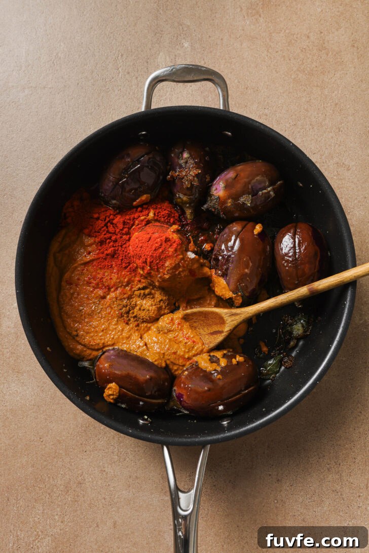Tomato paste, ground spices and salt added to skillet with eggplant.