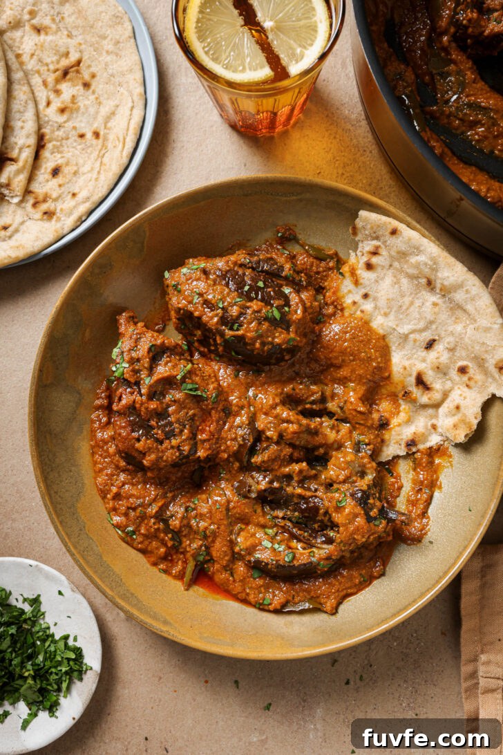 Bagare Baingan in a plate with a piece of roti garnished with minced cilantro.