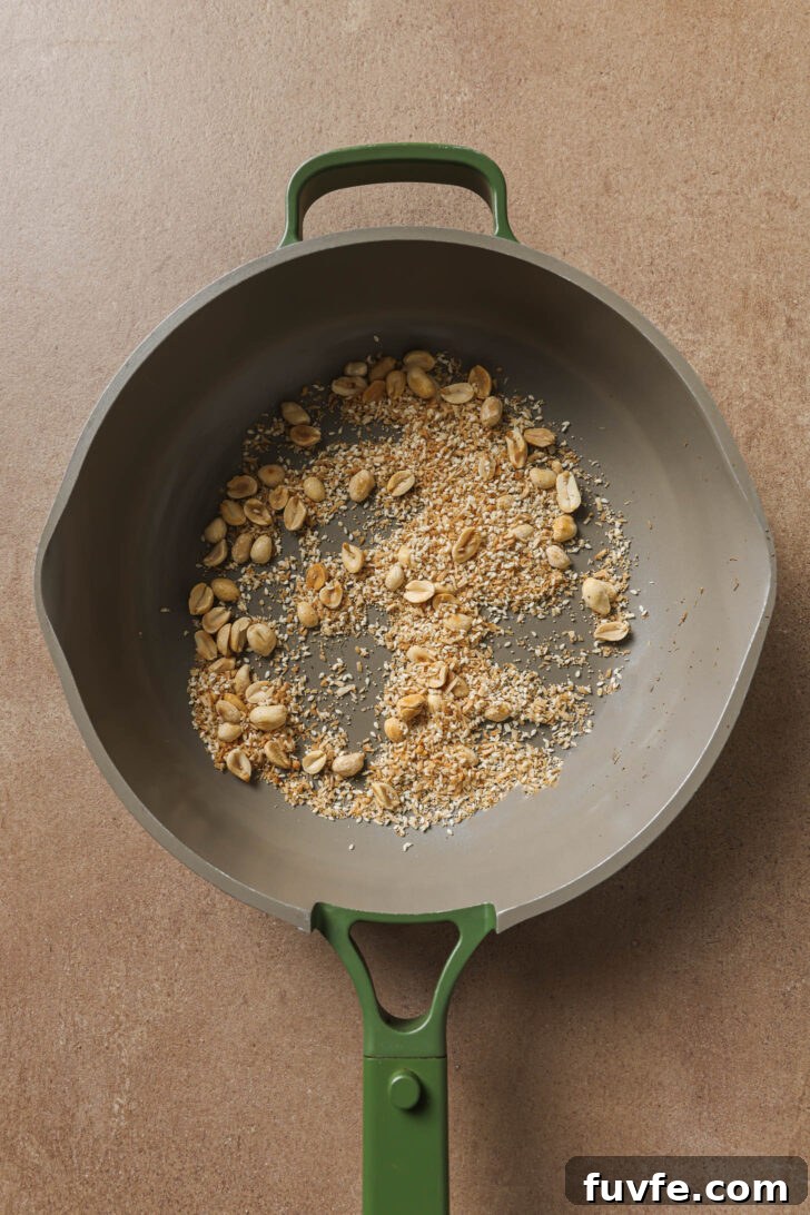 Coconut, poppy seeds and sesame seeds added to skillet with toasted peanuts.