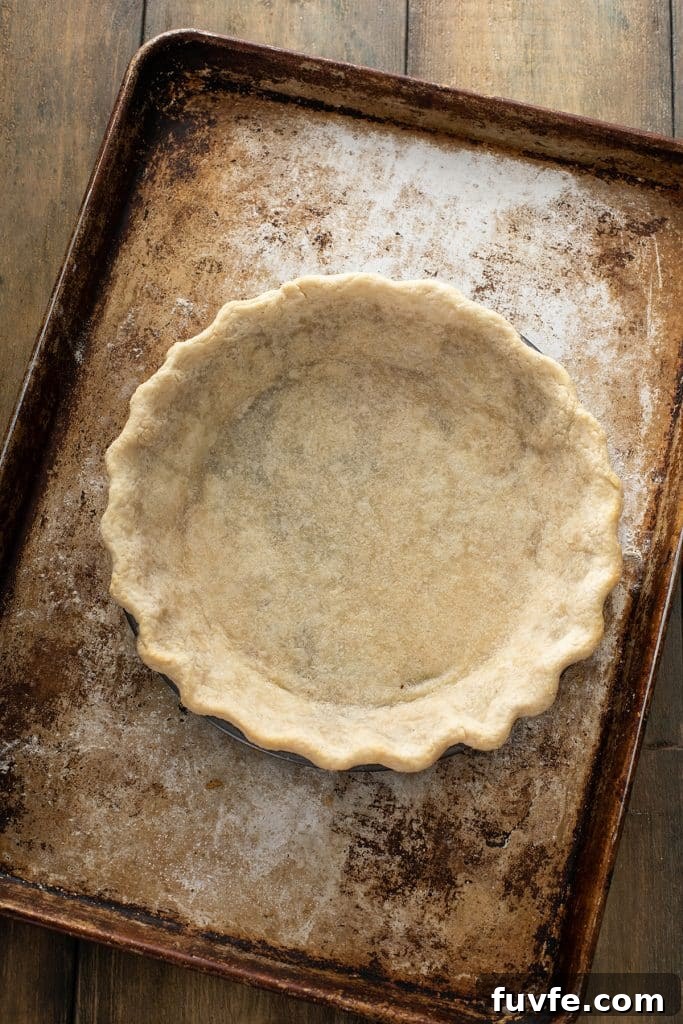 Baked pie crust in a pie dish over a baking tray