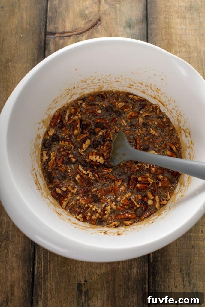 Chocolate pecan pie filling mixed in a large white bowl.