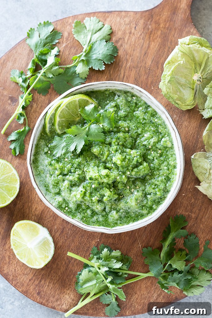 White bowl filled with green salsa with lime and cilantro on top