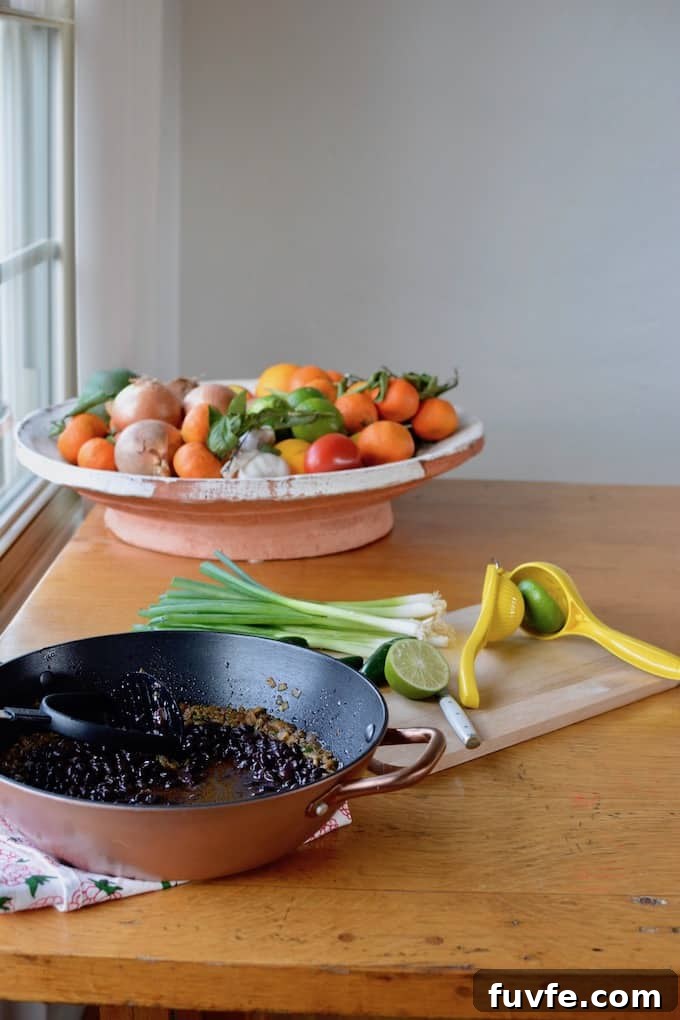 Quick Canned Black Beans Recipe for Flavorful Weeknight Meals 8 A copper pot of black beans sitting on a table next to a wooden cutting board and a fruit bowl.