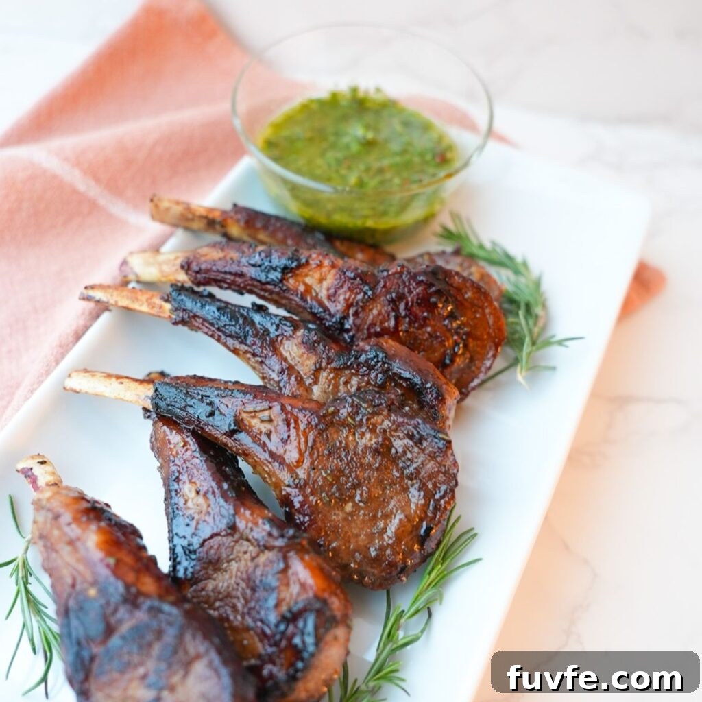 Juicy Garlic Butter Lamb Chops with Rosemary Guide 12 Lamb chops with a side of mint chimichurri on a plate with visible herbs and a glossy seared crust.