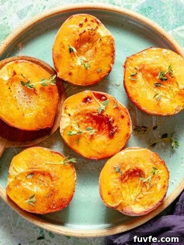 cooked peach halves on plate with wooden spoon.