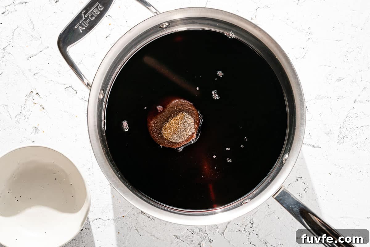 cinnamon stick, sugar and wine in saucepan