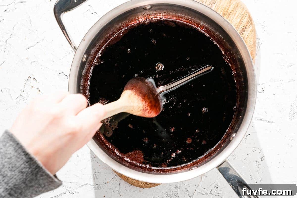 Spoon dragging through red wine syrup in saucepan