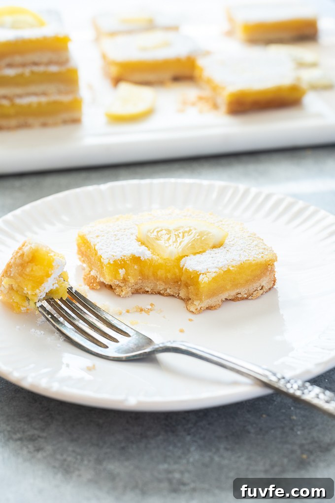 Lemon bar on a plate with bite taken out of it