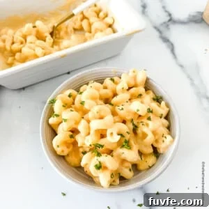 Creamy velveeta cheese sauce mixed with macaroni on a bowl and in a serving platter at the back.