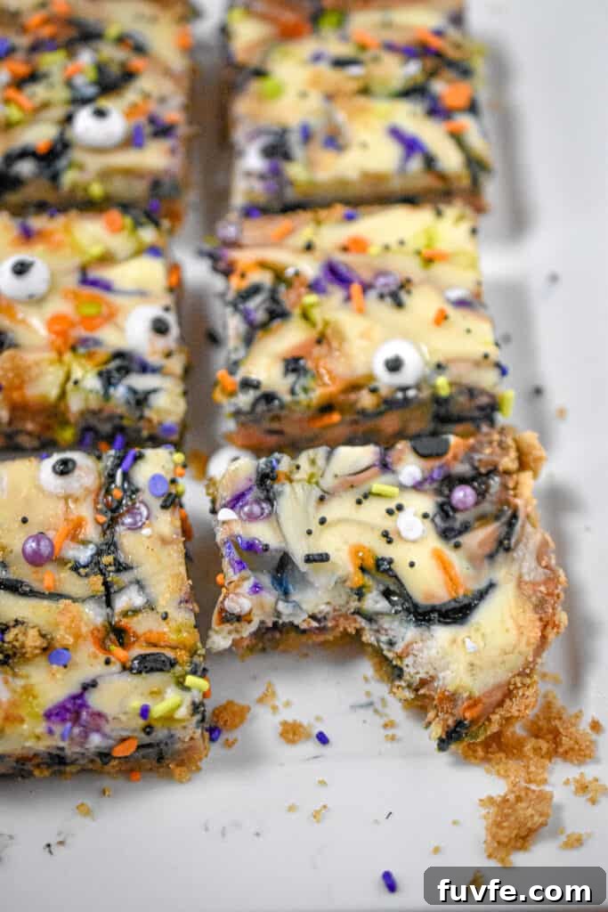 A bite of a Halloween cheesecake bar is on a plate with other cheesecake bars