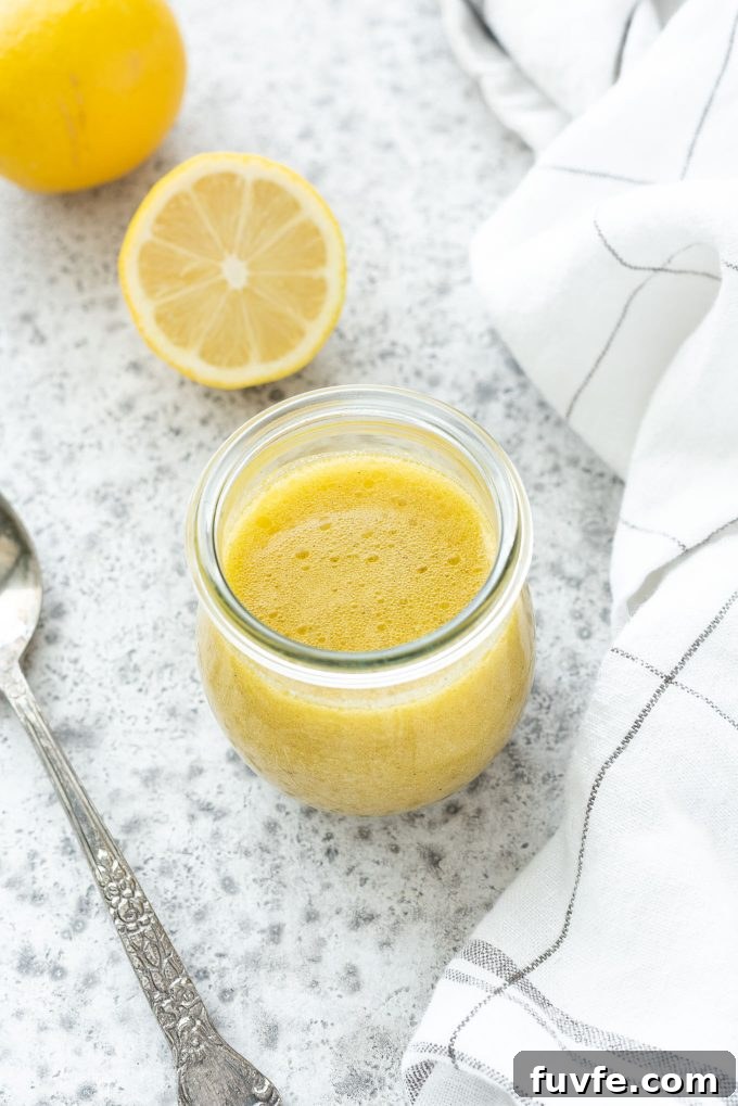 Lemon vinaigrette in a jar with a spoon nearby