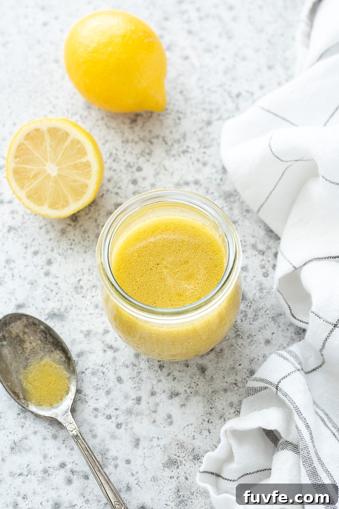 Lemon salad dressing in a jar with lemons and a spoon