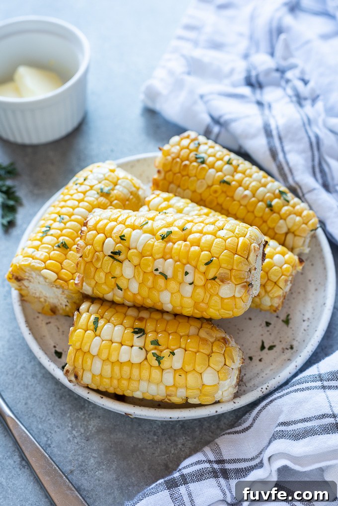 Air fryer corn on the cob on a serving plate with a linen alongside