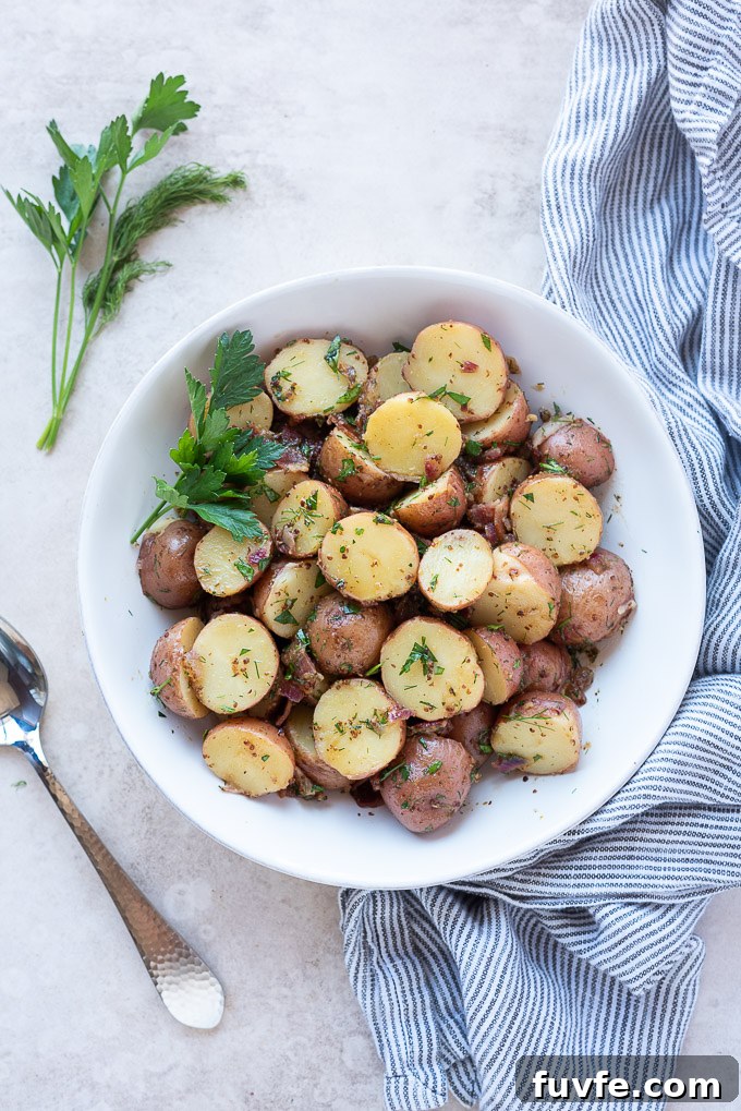 Authentic German Potato Salad Recipe 3 German potato salad in a white bowl with herbs and a linen