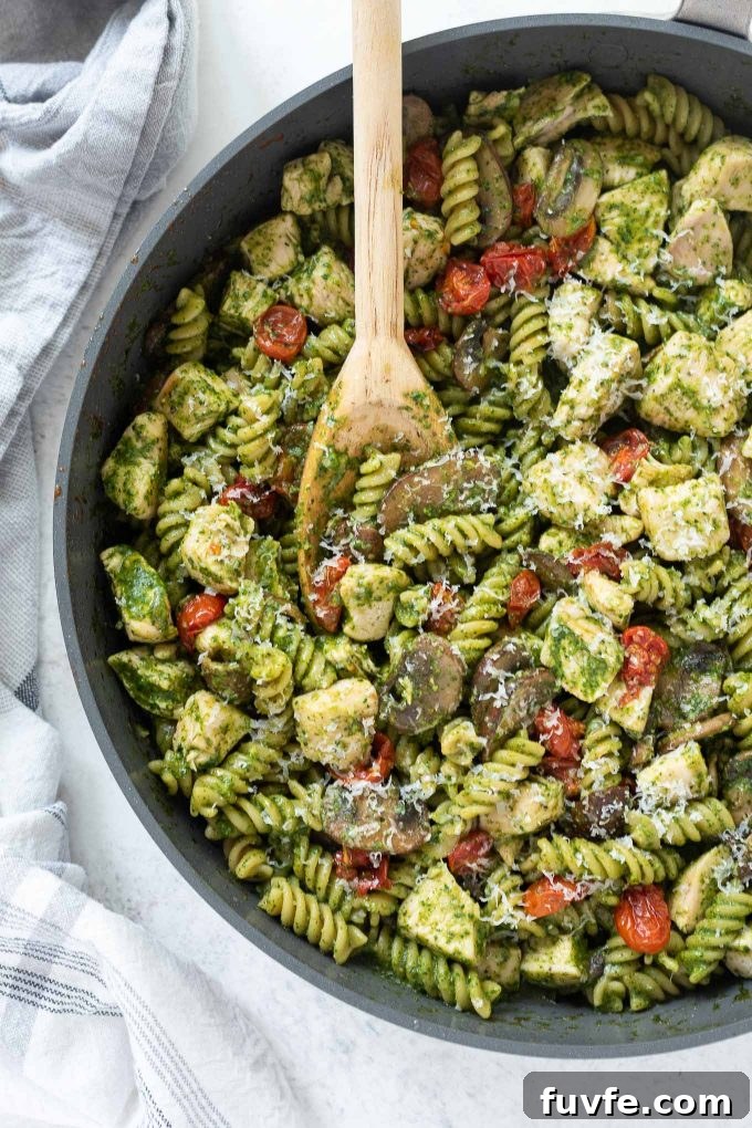 Chicken pesto pasta in a skillet with wooden spoon