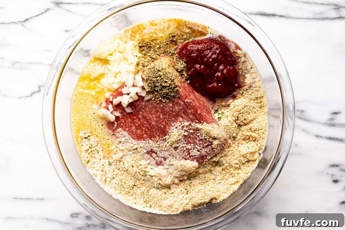 Glass bowl filled with ingredients to make meatloaf.