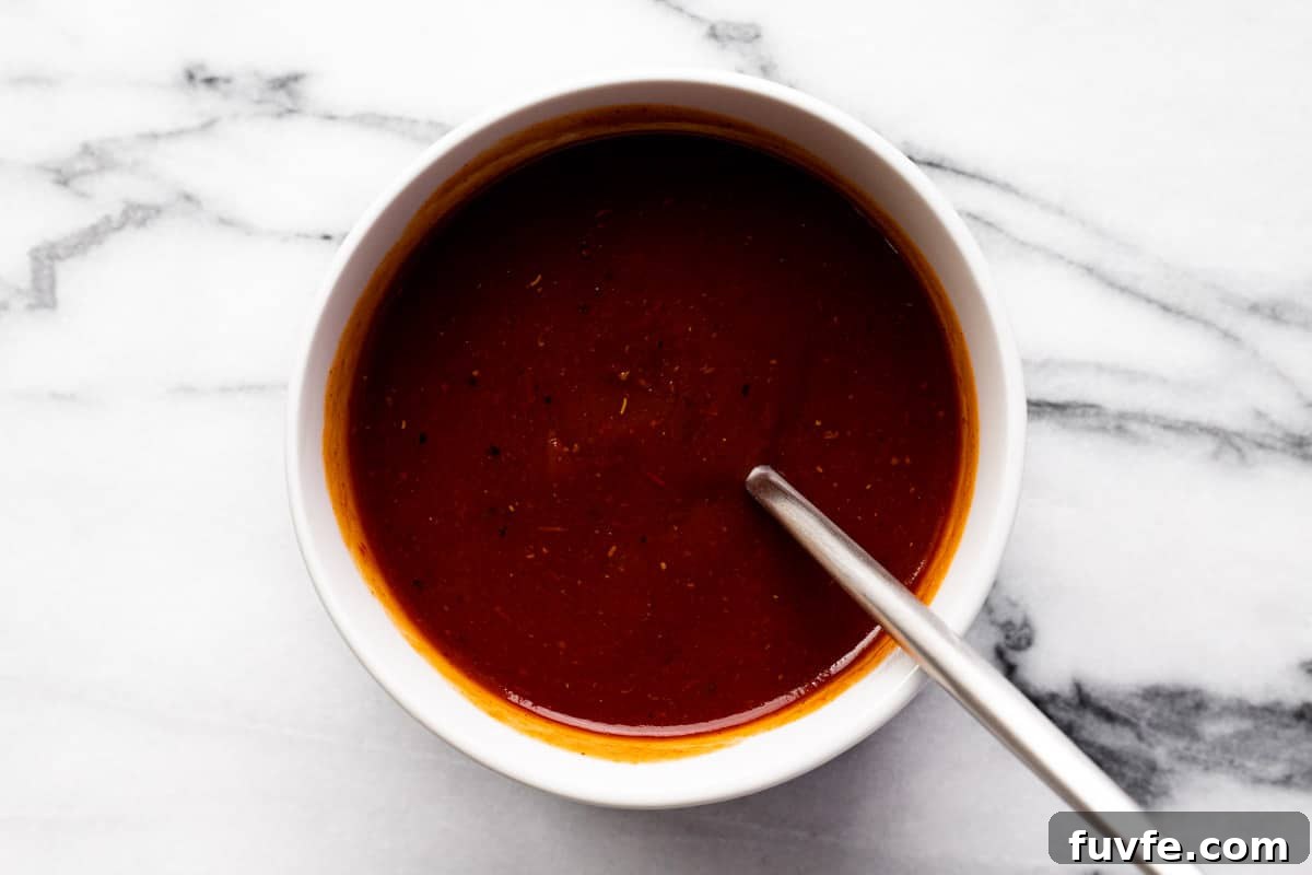 Small white bowl filled with chili sauce and barbecue sauce to top meatloaf.