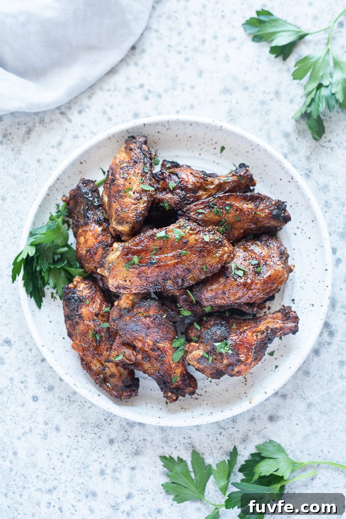 Air fryer chicken wings on a white plate with sprig of parsley