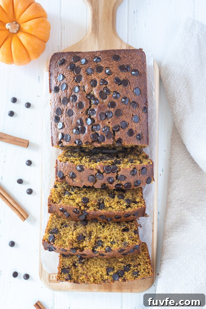 Loaf of pumpkin bread on a cutting board with half sliced
