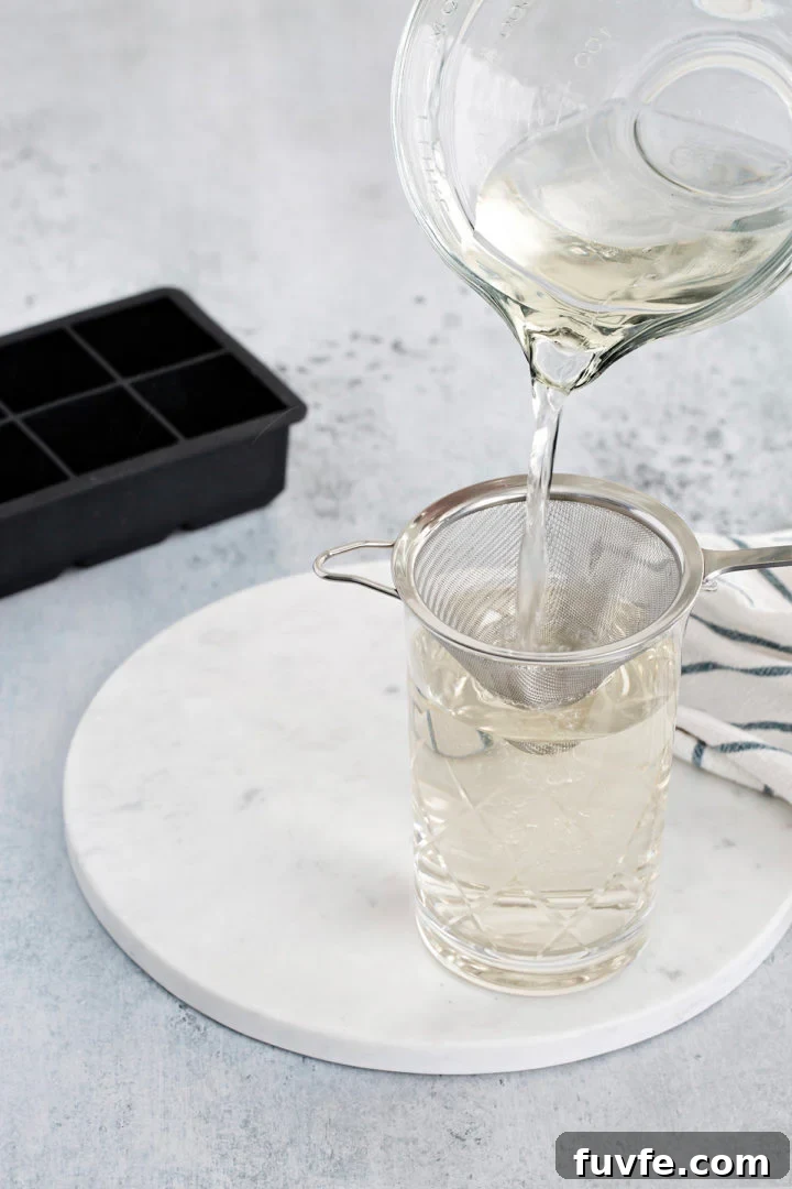 How to Make Smoked Ice at Home: Simple Steps for Cocktail Smoke Flavor 4 pouring smoked water through a strainer