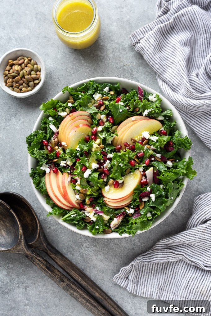 Kale apple salad in serving bowl with servers alongside