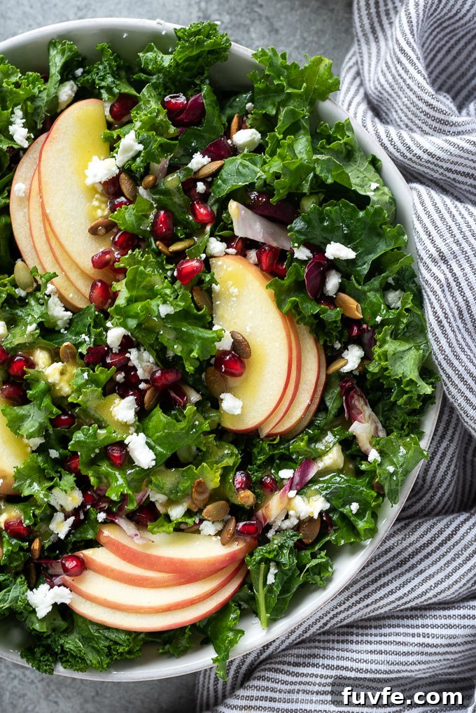 Kale and apple salad with pomegranate in a serving bowl
