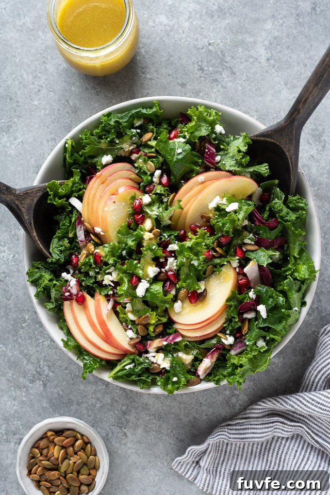 Kale and apple salad in a bowl with salad servers