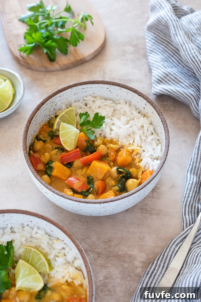Creamy Vegan Instant Pot Sweet Potato Chickpea Curry 3 Chickpea curry in a bowl with rice, lime wedges and cilantro