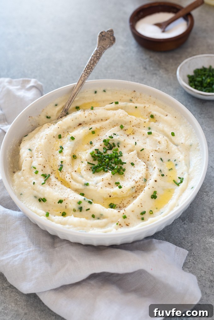 Garlic mashed cauliflower in a white bowl with a spoon
