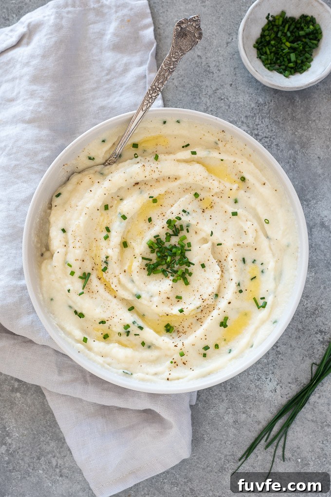Garlic mashed cauliflower in a bowl topped with butter and chives
