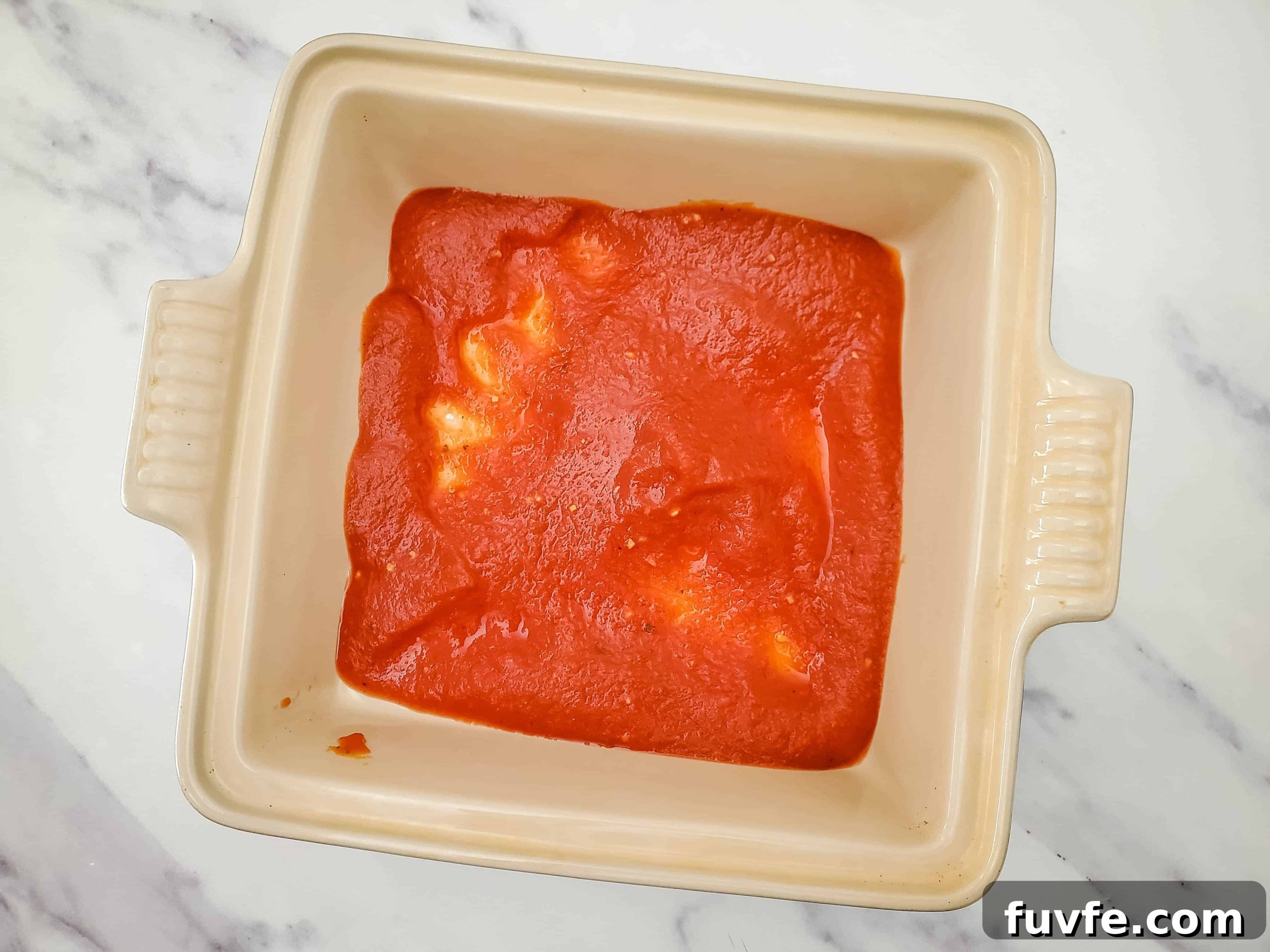 Quick Ravioli Lasagna Recipe for Fast Weeknight Dinners 4 Glass baking dish with layer of pasta sauce evenly distributed