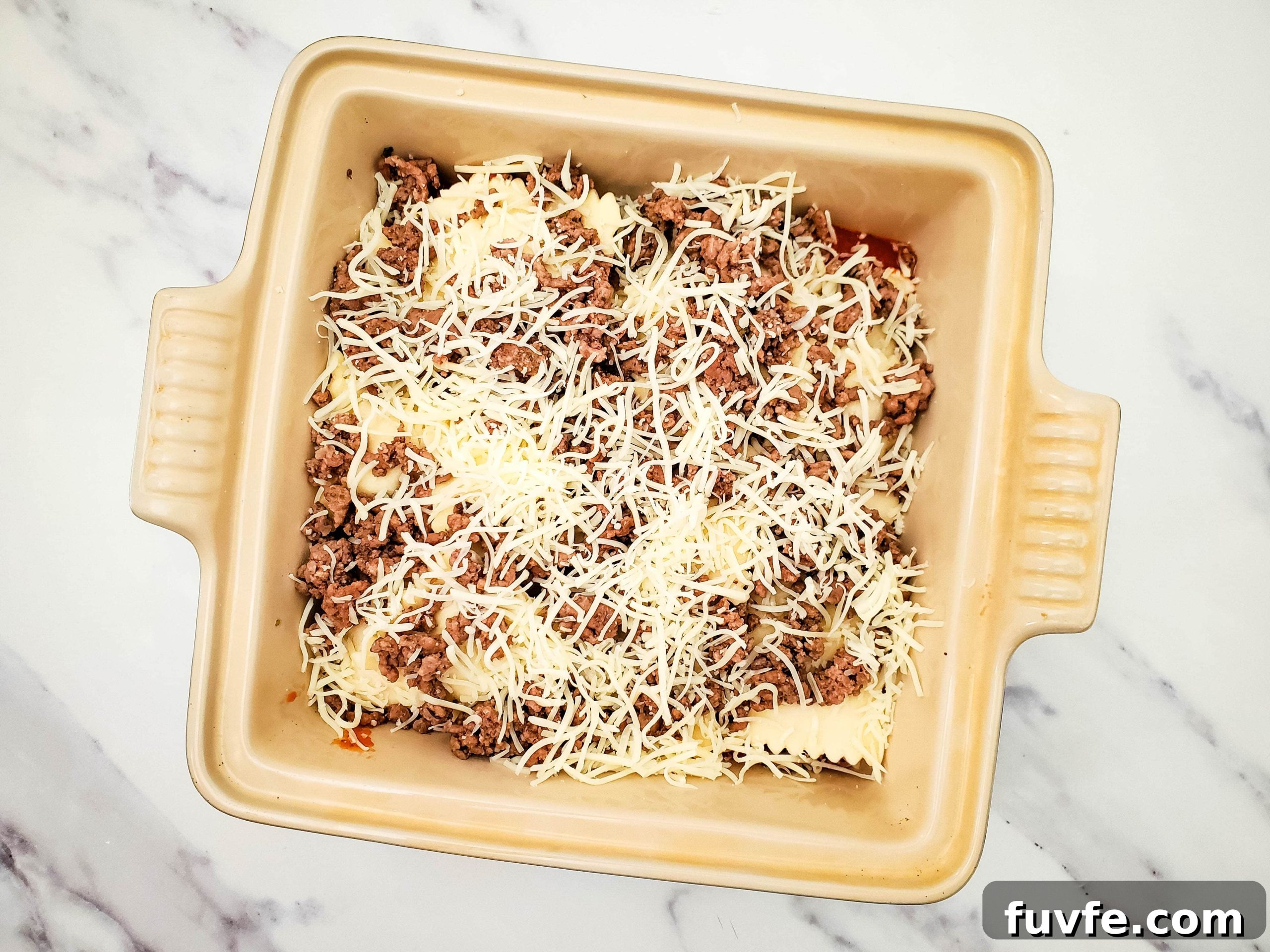 Quick Ravioli Lasagna Recipe for Fast Weeknight Dinners 6 Casserole baking dish with layered pasta sauce, frozen ravioli, ground beef, and mozzarella cheese