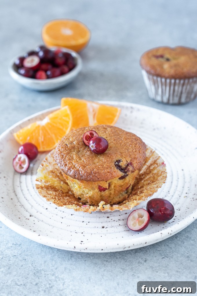 Cranberry orange muffin on a white plate with paper liner removed