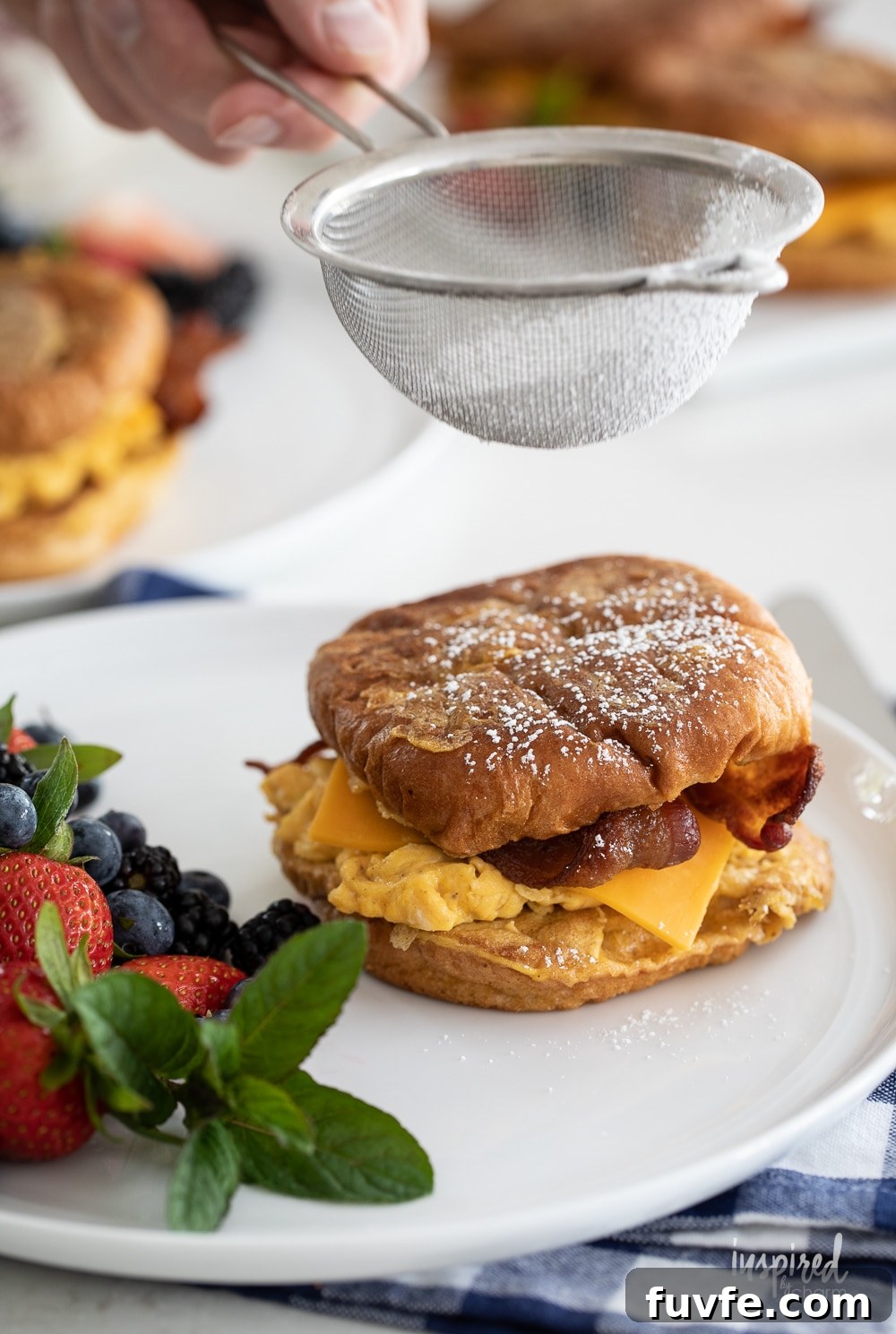 adding powdered sugar to french toast breakfast sandwiches.