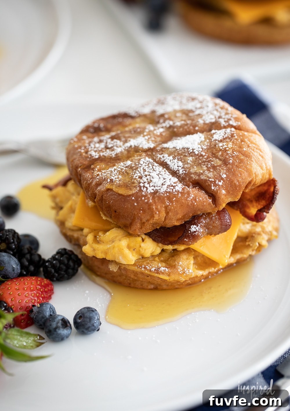 up close french toast breakfast sandwich on a plate with berries.